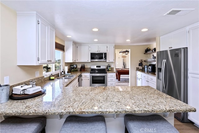 40125 Scanlon Rd, Temecula, CA 92592 - kitchen featuring appliances with stainless steel finishes, a sink, a peninsula, light stone counters, and recessed lighting