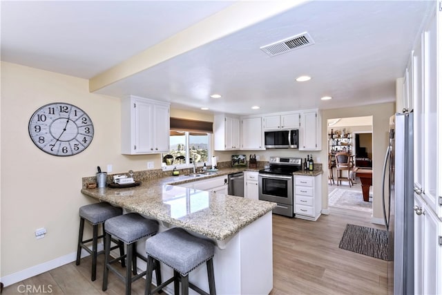 40125 Scanlon Rd, Temecula, CA 92592 - kitchen featuring appliances with stainless steel finishes, a peninsula, light stone counters, white cabinets, and a sink