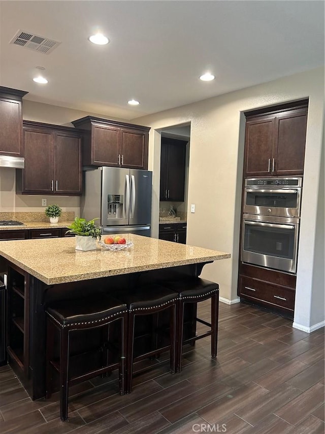 28626 Stonegate Ct, Valencia, CA 91354 - kitchen featuring stainless steel appliances, a breakfast bar, dark brown cabinetry, dark wood-type flooring, and open shelves