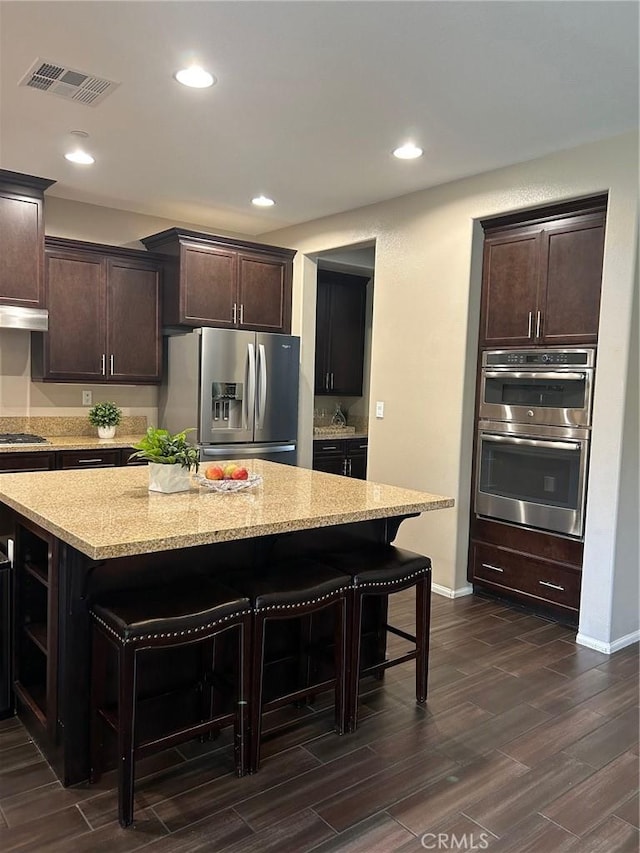 28626 Stonegate Ct, Valencia, CA 91354 - kitchen with stainless steel appliances, a breakfast bar area, dark brown cabinets, dark wood-type flooring, and open shelves