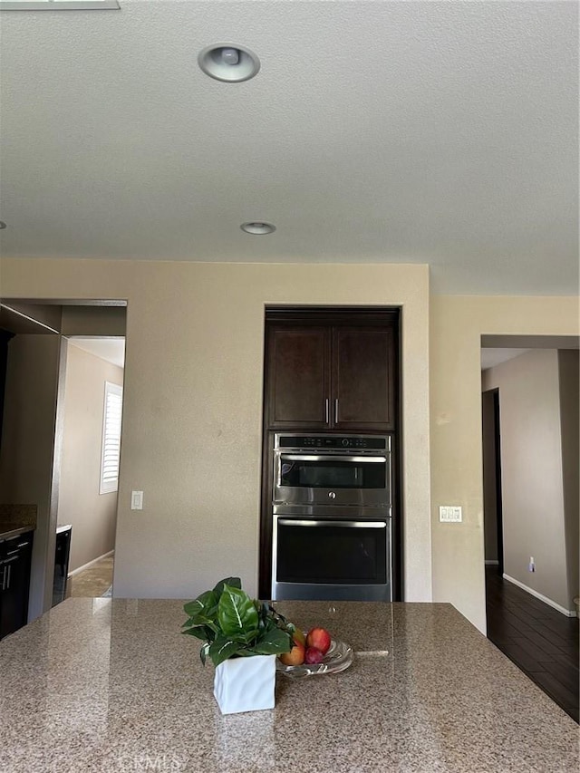 28626 Stonegate Ct, Valencia, CA 91354 - kitchen featuring dark brown cabinets, double oven, and stone countertops