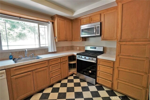 2306 S Encina St, Visalia, CA 93277 - kitchen with stainless steel appliances, a sink, tile countertops, light flooring, and brown cabinets