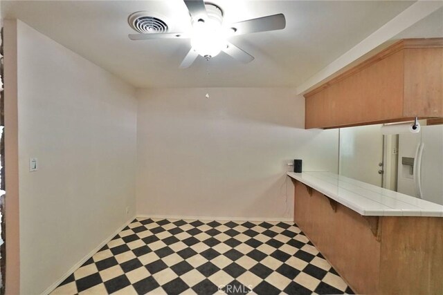 2306 S Encina St, Visalia, CA 93277 - interior space featuring light flooring, a ceiling fan, baseboards, tile countertops, and a kitchen bar