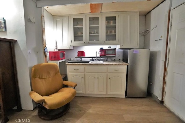2306 S Encina St, Visalia, CA 93277 - kitchen featuring freestanding refrigerator, a sink, light wood finished floors, glass insert cabinets, and white cabinetry