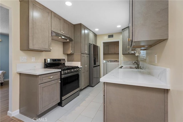 11747 Hollyview Dr, La Mirada, CA 90638 - kitchen featuring stainless steel appliances, under cabinet range hood, separate washer and dryer, a sink, and light stone counters