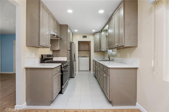 11747 Hollyview Dr, La Mirada, CA 90638 - kitchen featuring stainless steel gas range, baseboards, under cabinet range hood, separate washer and dryer, and a sink