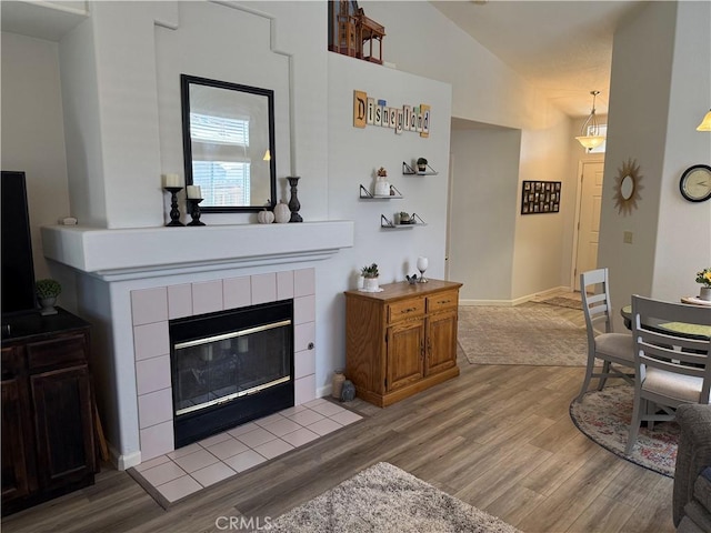 1438 Tumbleweed Ct, Oakdale, CA 95361 - living room with light wood-style floors, vaulted ceiling, a tile fireplace, and baseboards