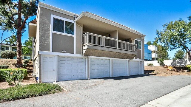23331 Caminito Basilio Unit 348, Laguna Hills, CA 92653 - view of front of home featuring a balcony, an attached garage, stucco siding, and asphalt driveway
