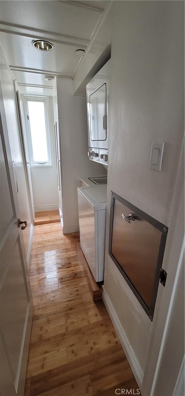 448 N Oakhurst Dr Unit 1, Beverly Hills, CA 90210 - laundry room featuring stacked washer / dryer, light wood-style flooring, and baseboards