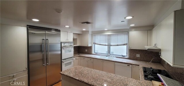448 N Oakhurst Dr Unit 1, Beverly Hills, CA 90210 - kitchen with stainless steel built in refrigerator, under cabinet range hood, double oven, decorative backsplash, and white cabinets