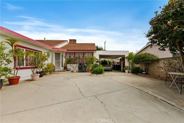 1140 Indian Summer Ave, La Puente, CA 91744 - view of front facade with concrete driveway, stucco siding, a carport, a shingled roof, and a chimney
