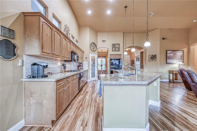 2737 Sussex Ave, Clovis, CA 93611 - kitchen featuring black appliances, light wood-type flooring, baseboards, and a towering ceiling