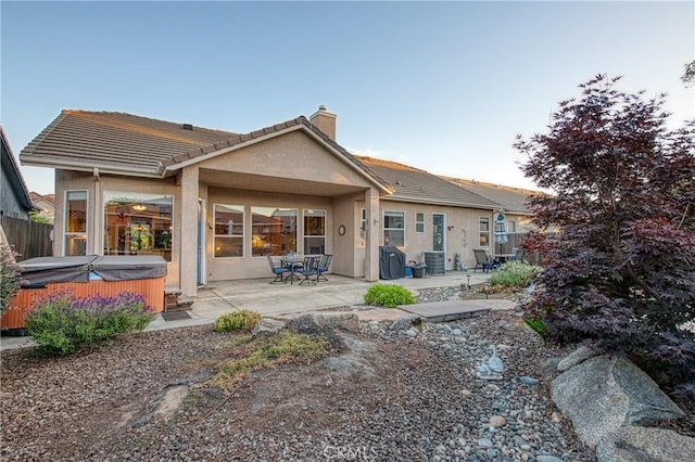 2737 Sussex Ave, Clovis, CA 93611 - rear view of house with a hot tub, a chimney, a patio, stucco siding, and a tiled roof