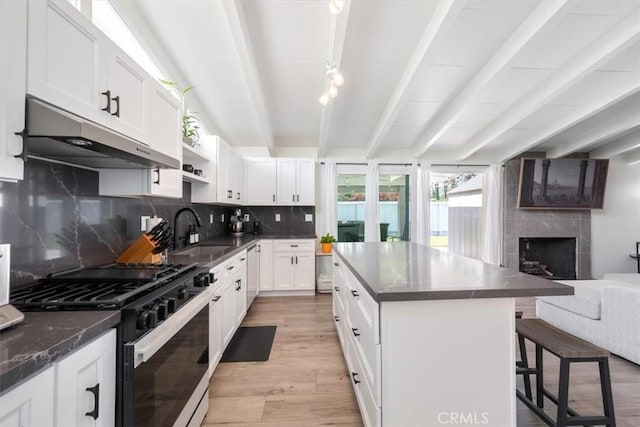 19842 Gilmore St, Woodland Hills, CA 91367 - kitchen with black gas stove, dark countertops, under cabinet range hood, light wood-style flooring, and beam ceiling