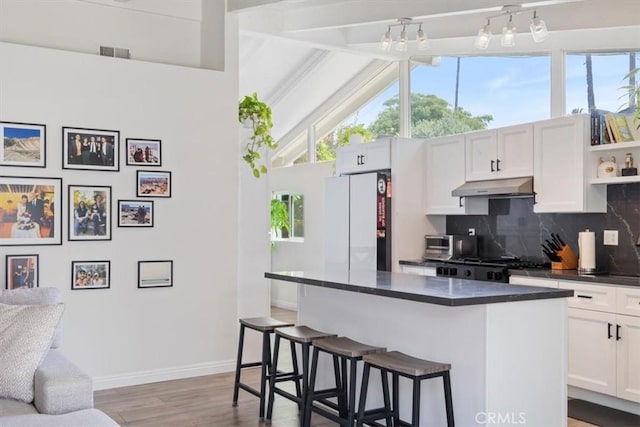 19842 Gilmore St, Woodland Hills, CA 91367 - kitchen with under cabinet range hood, dark countertops, freestanding refrigerator, wood finished floors, and a kitchen breakfast bar