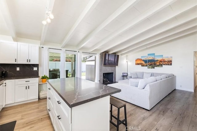 19842 Gilmore St, Woodland Hills, CA 91367 - kitchen featuring a breakfast bar, light wood-style flooring, decorative backsplash, a large fireplace, and white cabinets