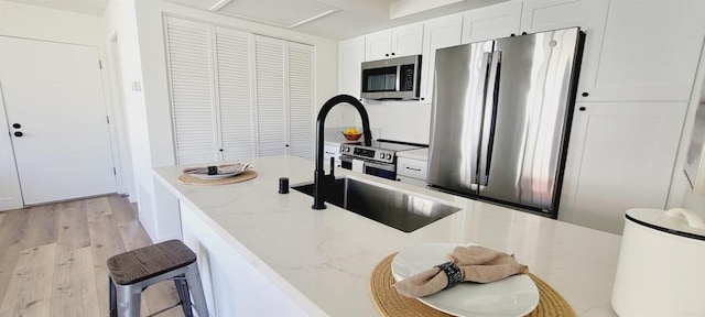742 Eastshore, Chula Vista, CA 91913 - kitchen featuring stainless steel appliances, light wood finished floors, white cabinetry, light stone countertops, and a sink