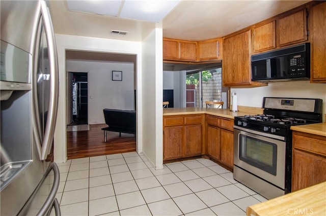 28948 Marilyn Dr, Canyon Country, CA 91387 - kitchen with stainless steel appliances, light countertops, brown cabinets, and light tile patterned flooring