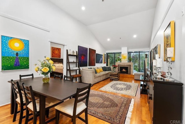 270 Cagney Ln Unit 315, Newport Beach, CA 92663 - dining area with high vaulted ceiling, light wood-style flooring, a warm lit fireplace, and recessed lighting