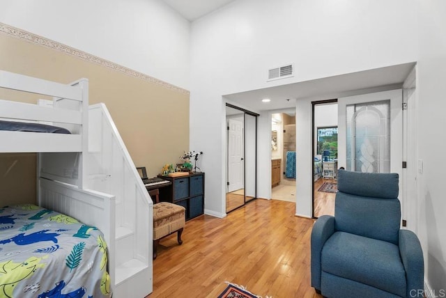 270 Cagney Ln Unit 315, Newport Beach, CA 92663 - bedroom featuring light wood-style floors, baseboards, ensuite bathroom, and a towering ceiling