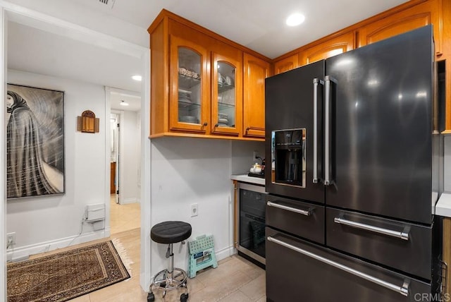 270 Cagney Ln Unit 315, Newport Beach, CA 92663 - kitchen featuring high end refrigerator, brown cabinets, glass insert cabinets, light tile patterned floors, and baseboards