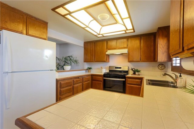 949 W Imperial Blvd Unit 14C, La Habra, CA 90631 - kitchen featuring freestanding refrigerator, stainless steel gas range oven, under cabinet range hood, brown cabinets, and a peninsula