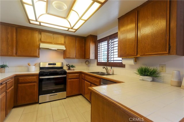 949 W Imperial Blvd Unit 14C, La Habra, CA 90631 - kitchen featuring stainless steel range with gas cooktop, under cabinet range hood, brown cabinets, tile counters, and light tile patterned floors