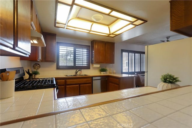 949 W Imperial Blvd Unit 14C, La Habra, CA 90631 - kitchen with stainless steel dishwasher, under cabinet range hood, range with gas cooktop, tile counters, and brown cabinetry