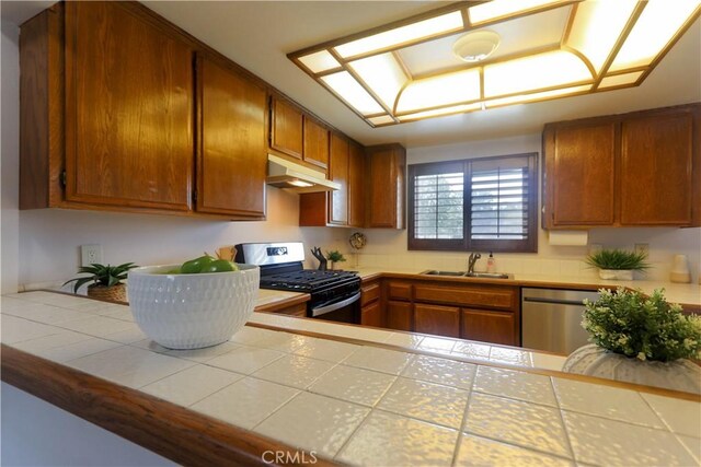 949 W Imperial Blvd Unit 14C, La Habra, CA 90631 - kitchen featuring appliances with stainless steel finishes, under cabinet range hood, tile countertops, and brown cabinets