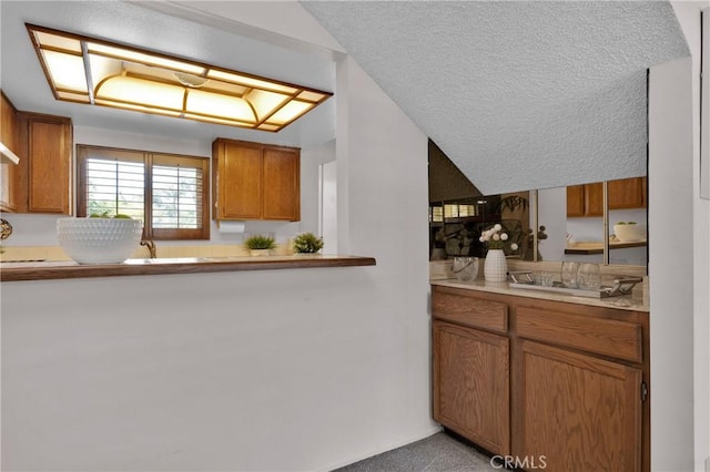949 W Imperial Blvd Unit 14C, La Habra, CA 90631 - kitchen with brown cabinetry, a textured ceiling, light countertops, and light colored carpet