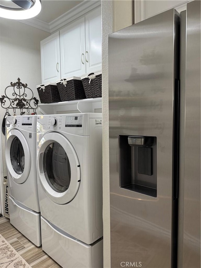 41410 Juniper St Unit 2012, Murrieta, CA 92562 - washroom with ornamental molding, washer and dryer, light wood-style floors, and cabinet space