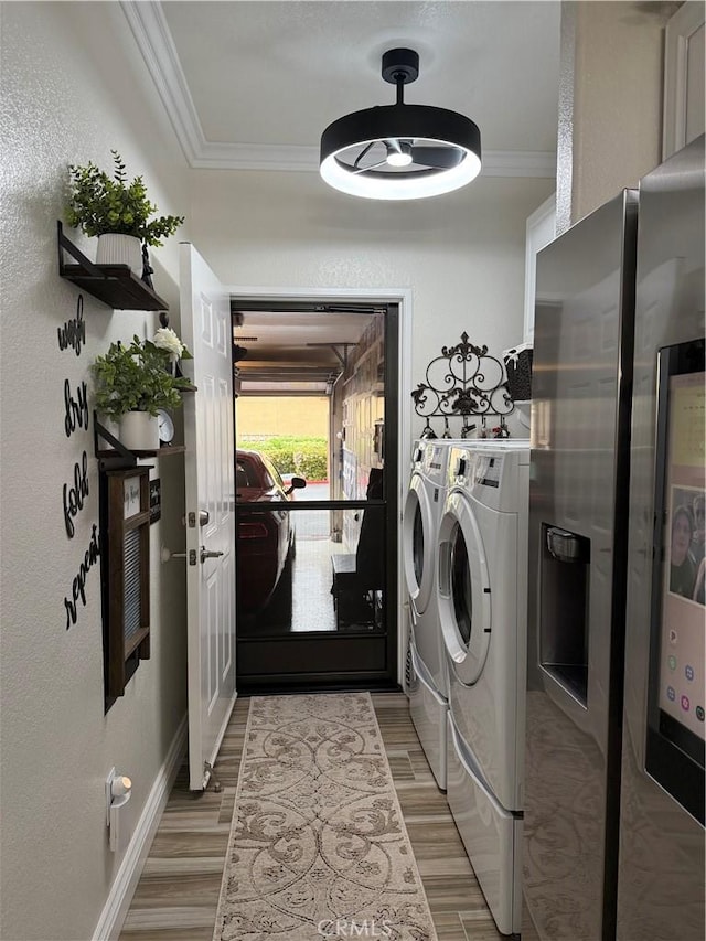 41410 Juniper St Unit 2012, Murrieta, CA 92562 - laundry room featuring crown molding, washing machine and dryer, light wood-style flooring, baseboards, and a textured wall
