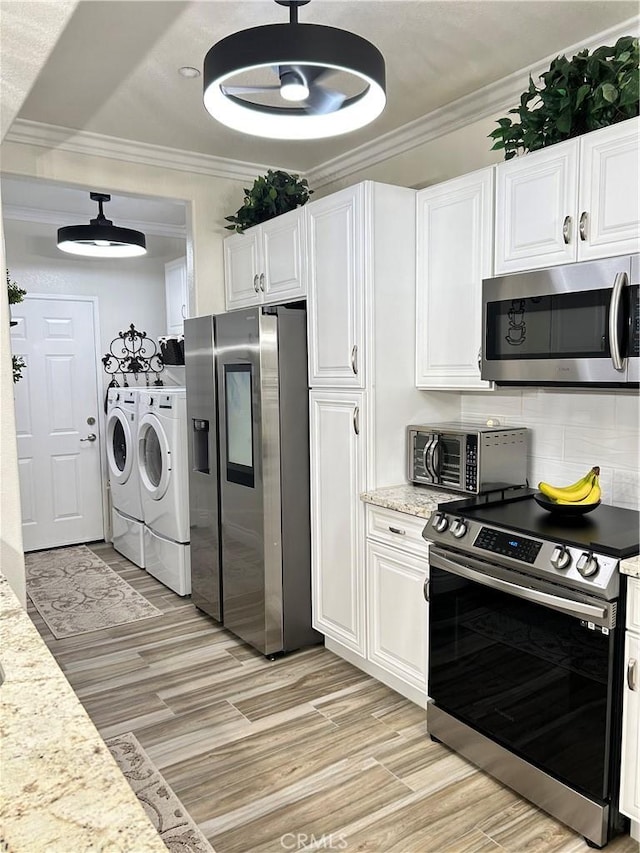 41410 Juniper St Unit 2012, Murrieta, CA 92562 - kitchen with washing machine and dryer, stainless steel appliances, light wood-type flooring, white cabinets, and decorative backsplash