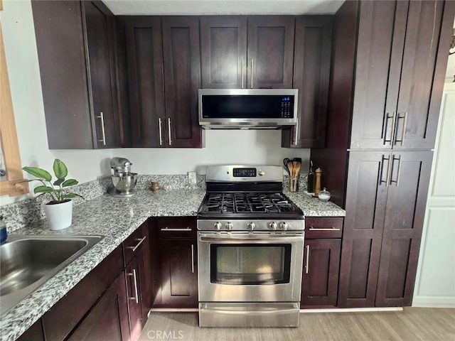 1707 Alta St, Redlands, CA 92374 - kitchen featuring appliances with stainless steel finishes, a sink, light stone countertops, and dark brown cabinets