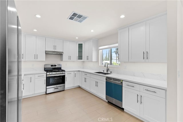 7714 Kyle St, Tujunga, CA 91042 - kitchen featuring appliances with stainless steel finishes, a sink, under cabinet range hood, white cabinets, and recessed lighting