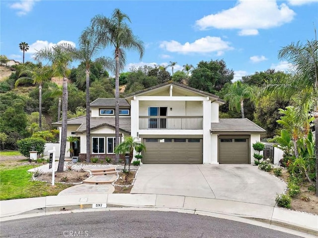 597 Rancheria Rd, Diamond Bar, CA 91765 - view of front facade featuring a balcony, concrete driveway, stucco siding, an attached garage, and view of wooded area