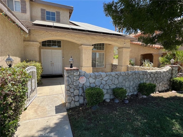 12413 Redrock Rd, Victorville, CA 92392 - view of exterior entry with stucco siding, solar panels, and a porch