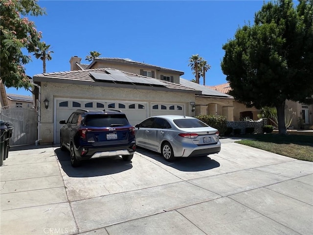 12413 Redrock Rd, Victorville, CA 92392 - view of front facade with concrete driveway, a garage, roof mounted solar panels, and a chimney
