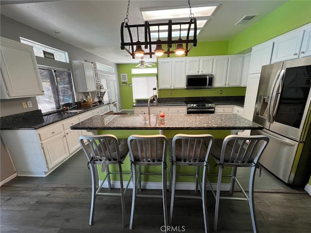 12413 Redrock Rd, Victorville, CA 92392 - kitchen with appliances with stainless steel finishes, white cabinets, a center island with sink, and a kitchen breakfast bar