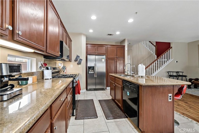 37814 Veranda Way, Murrieta, CA 92563 - kitchen featuring appliances with stainless steel finishes, a breakfast bar, light tile patterned floors, light stone counters, and a sink