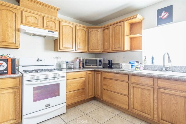 14752 Grafton Ln, Helendale, CA 92342 - kitchen featuring white gas stove, stainless steel microwave, under cabinet range hood, a sink, and light tile patterned floors