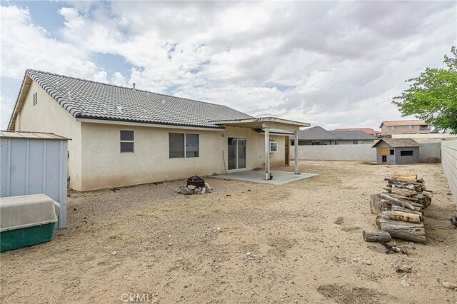 14752 Grafton Ln, Helendale, CA 92342 - rear view of property with stucco siding, a fenced backyard, a patio, a fire pit, and a tiled roof