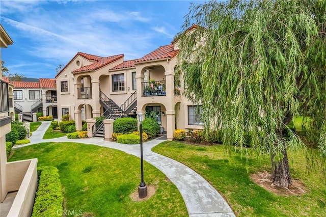 13219 Wimberly Sq Unit 306, San Diego, CA 92128 - mediterranean / spanish-style house with a tile roof, stucco siding, stairway, and a front lawn