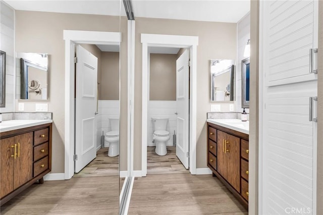 13219 Wimberly Sq Unit 306, San Diego, CA 92128 - full bathroom featuring toilet, wood finished floors, two vanities, and wainscoting