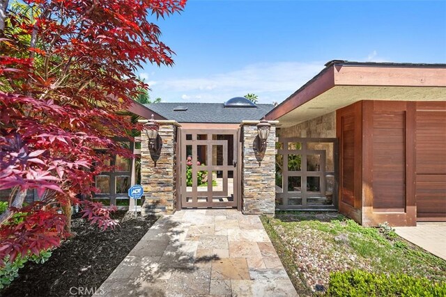 27121 Shenandoah Dr, Laguna Hills, CA 92653 - doorway to property featuring stone siding and a shingled roof