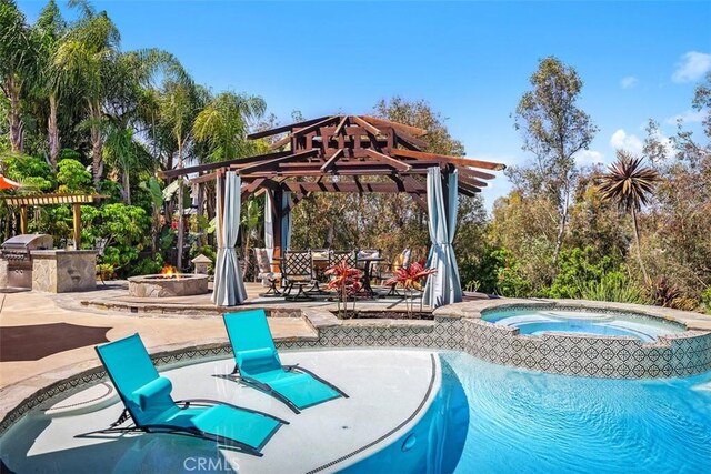 27121 Shenandoah Dr, Laguna Hills, CA 92653 - outdoor pool featuring an outdoor kitchen, an in-ground hot tub, an outdoor fire pit, a patio, and view of wooded area