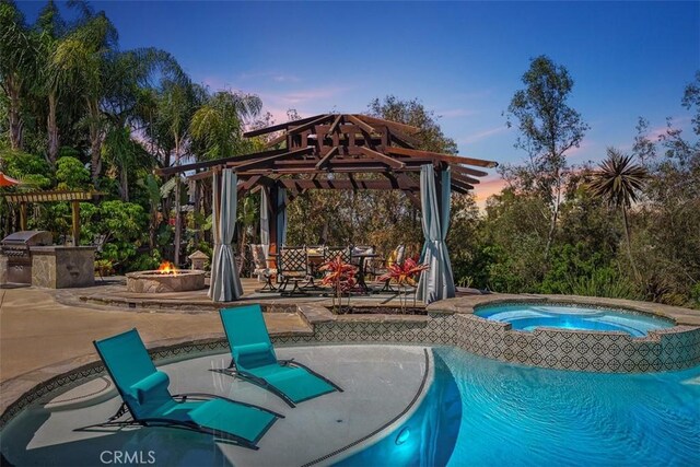 27121 Shenandoah Dr, Laguna Hills, CA 92653 - pool at dusk with a fire pit, a gazebo, an in-ground hot tub, an outdoor kitchen, and a patio