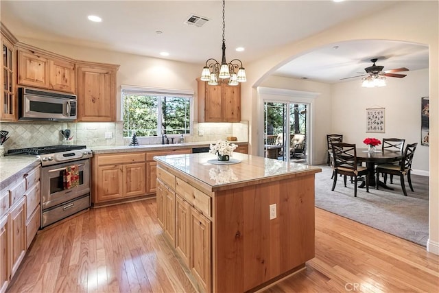 27376 Pinewood Dr, Lake Arrowhead, CA 92352 - kitchen featuring appliances with stainless steel finishes, arched walkways, light wood finished floors, tasteful backsplash, and recessed lighting