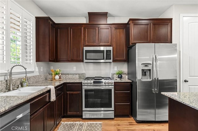 3274 Tinker Creek Way, Chico, CA 95973 - kitchen featuring appliances with stainless steel finishes, a sink, light wood-style floors, light stone counters, and dark brown cabinets