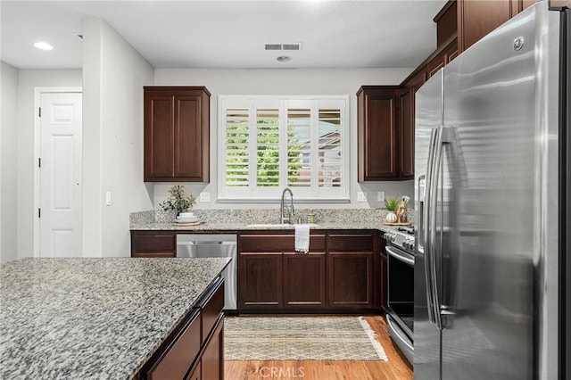 3274 Tinker Creek Way, Chico, CA 95973 - kitchen featuring appliances with stainless steel finishes, a sink, light wood finished floors, light stone counters, and dark brown cabinets